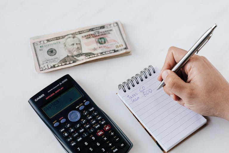 Primer plano de los elementos del presupuesto, incluida la calculadora, el efectivo y el cuaderno para la planificación financiera simbolizando finanzas personales básicas.