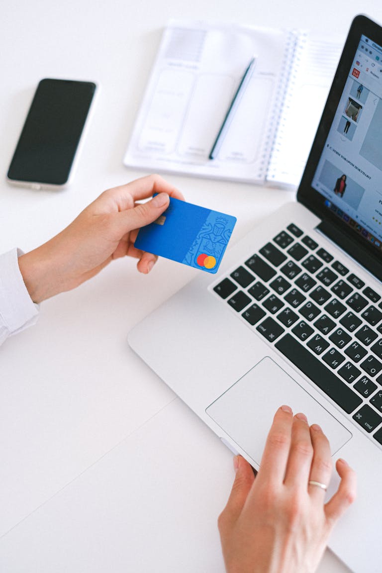 Persona realizando una compra en línea con una tarjeta de crédito en una computadora portátil, mostrando tecnología moderna y endeudamiento responsable.
