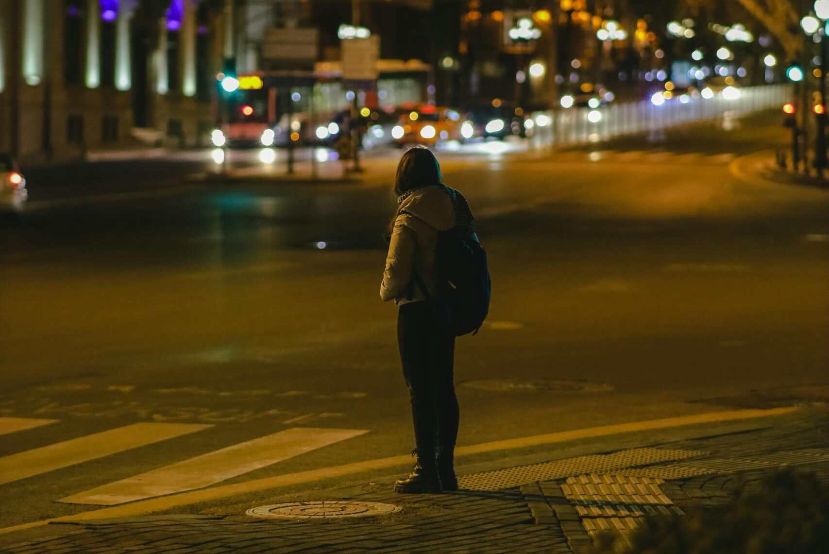 Una persona se encuentra en una encrucijada en Ankara, Turquía, por la noche, rodeada de edificios iluminados y farolas, haciendo referencia a la construcción de un camino de riqueza.