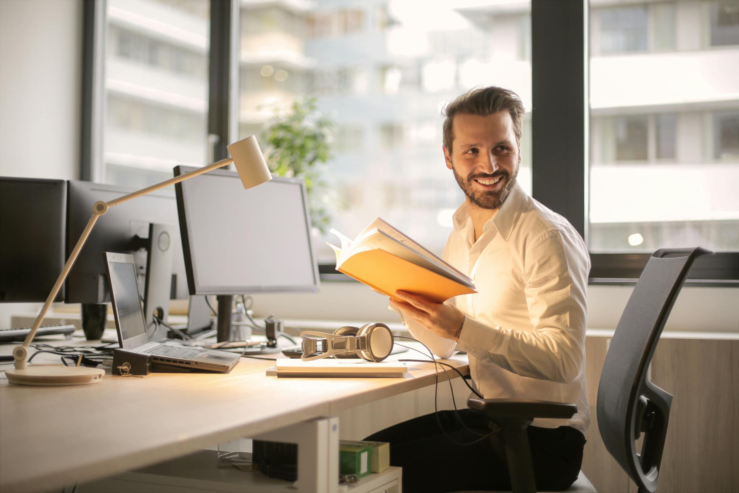 Un hombre de negocios relajado disfrutando de un descanso en su luminoso y contemporáneo entorno de oficina simbolizando sanación de heridas monetarias.