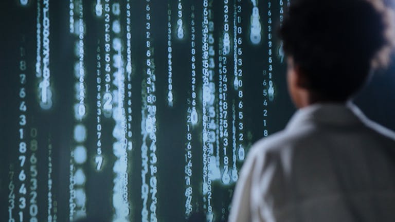 Una persona mirando números brillantes en una pantalla, que simbolizan proteger datos y dinero en internet.
