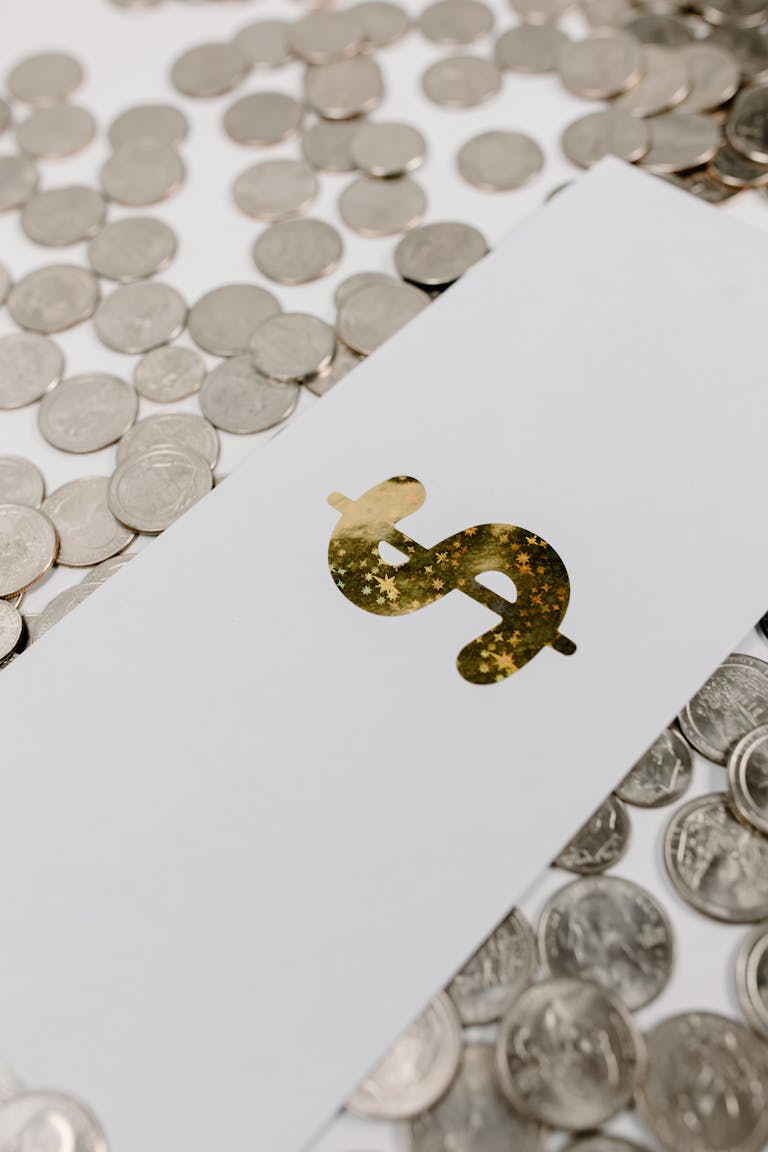 Primer plano de un signo de dólar dorado sobre papel entre monedas dispersas, que simboliza fortuna neta.