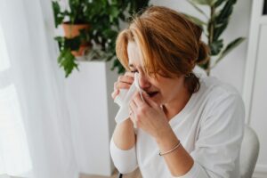 Mujer estresada calculando gastos y deudas con recibos y facturas en casa simbolizando una mala relación con el dinero.
