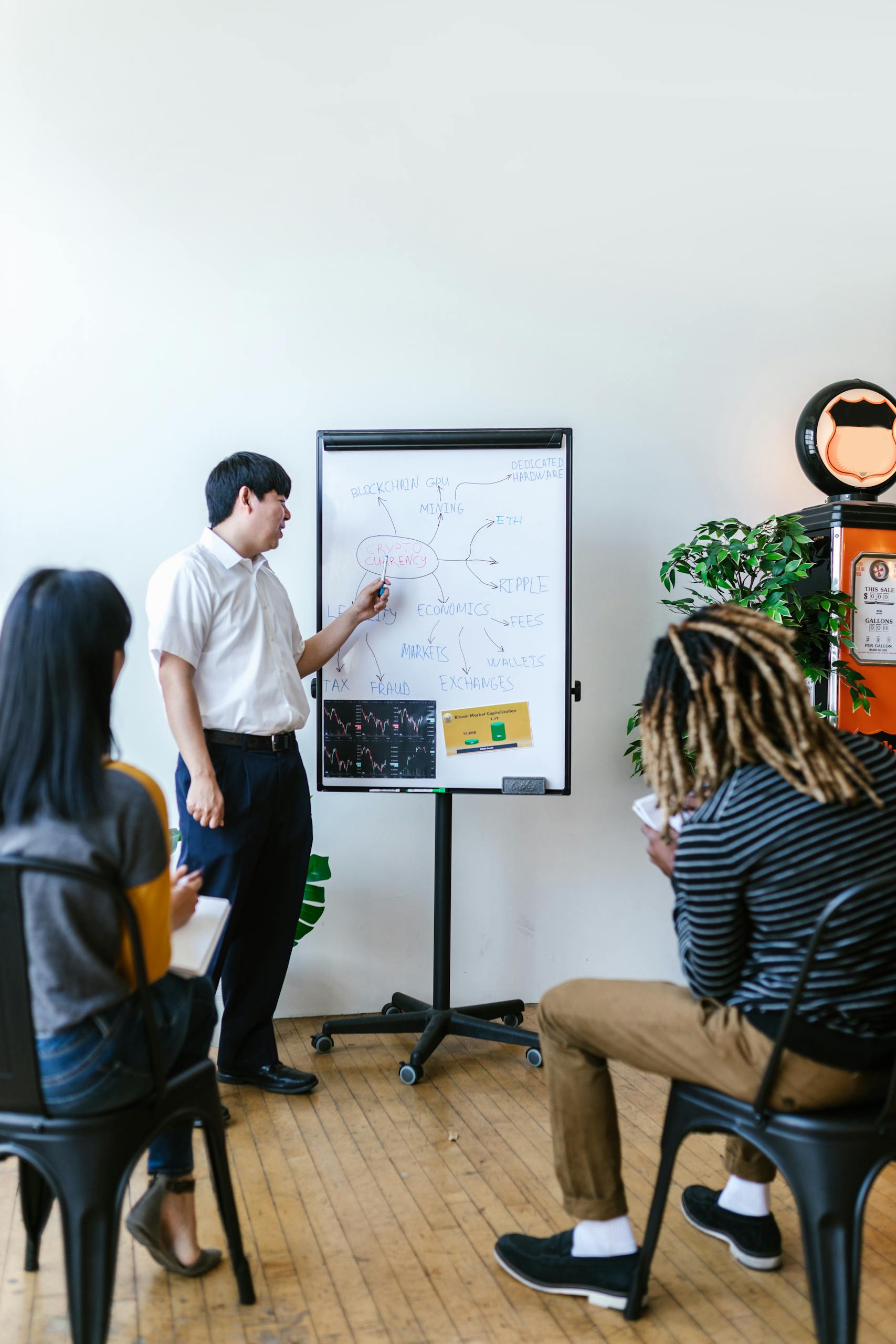Capacitador dando una presentación sobre educación financiera para jóvenes a un grupo diverso en una oficina moderna.