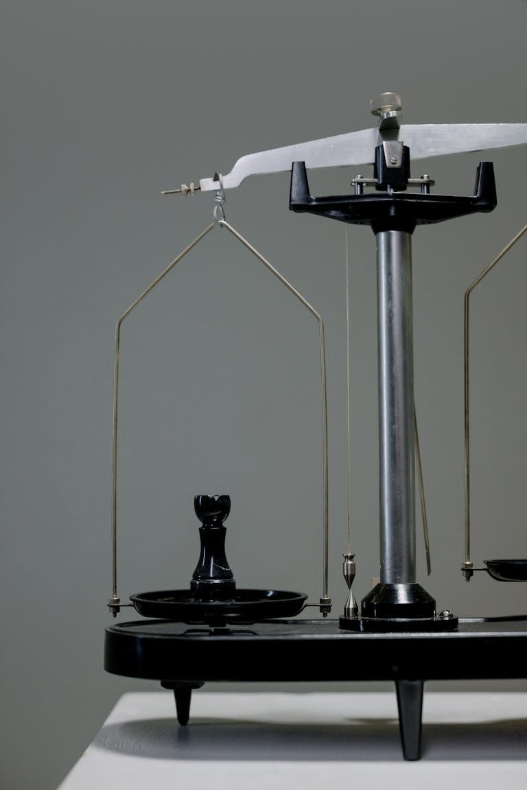 Primer plano de una balanza antigua con una pieza de ajedrez equilibrándose conceptualmente simbolizando un perfil de inversor moderado.