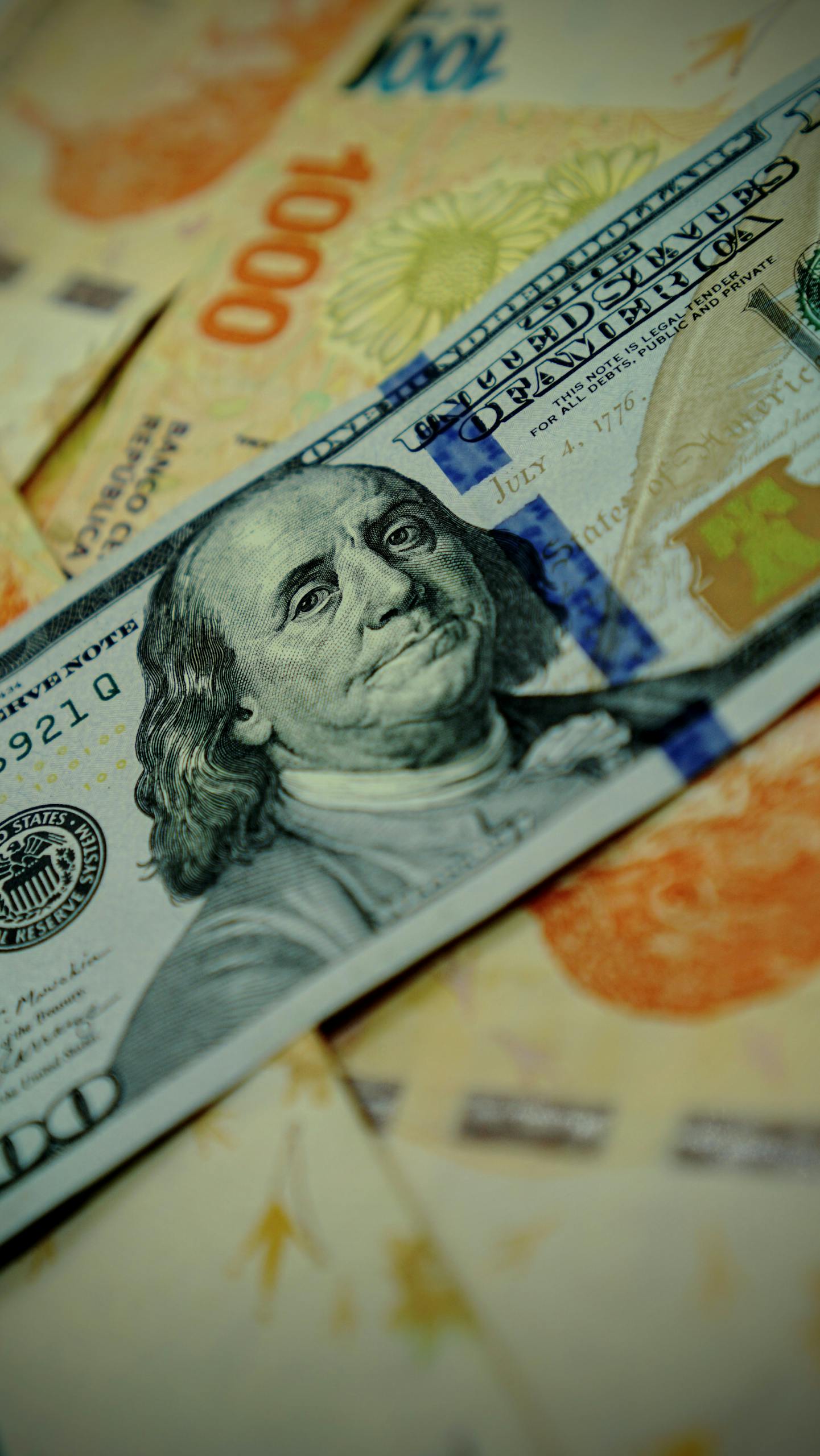 Imagen detallada de billetes de dólares estadounidenses y pesos argentinos resaltando el cambio de moneda.