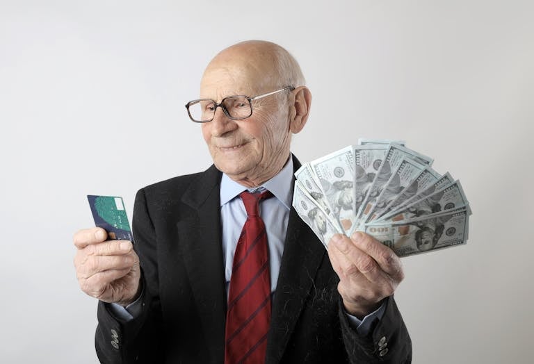 Un anciano con traje decide entre una tarjeta de crédito o préstamo.