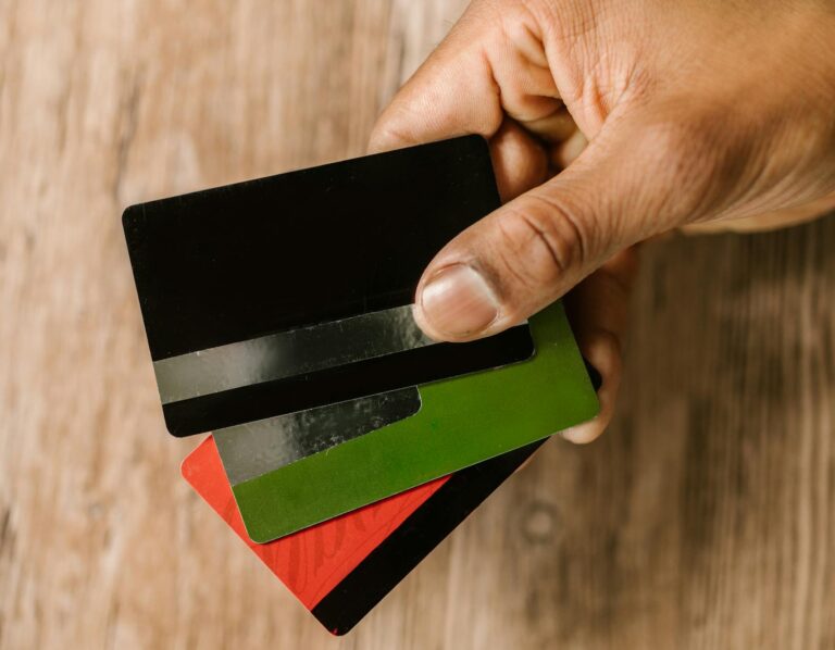 Una mano que sostiene varias tarjetas de crédito sobre un fondo de madera, enfatizando cómo mejorar historial crediticio.