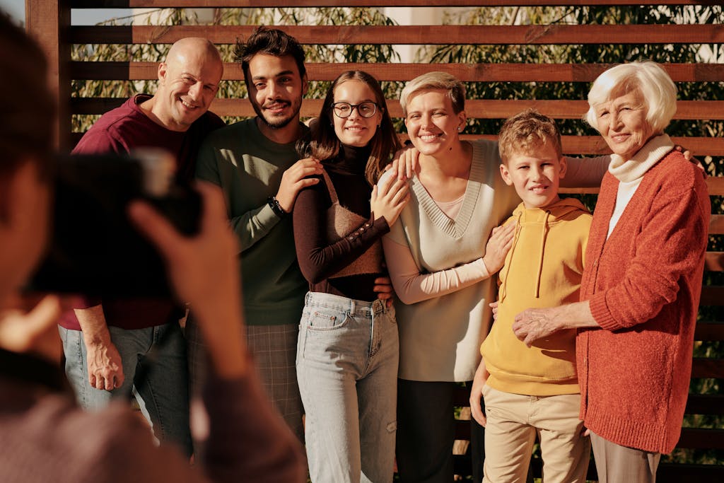 Un alegre retrato familiar que muestra a varias generaciones sonriendo al aire libre bajo la luz del día, representando autocontrol y límites emocionales.