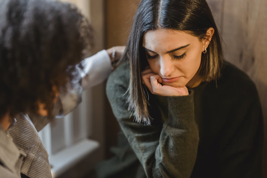 Una mujer cultivadora le da una palmada en el hombro a su amiga, consolándola mientras están sentadas juntas en casa, representando la riqueza es libertad.